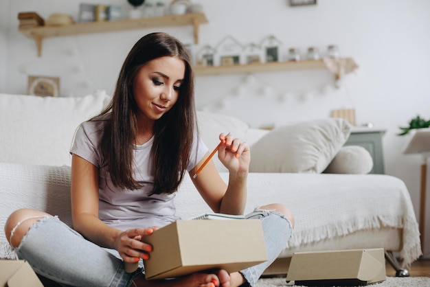 Une fille a une petite entreprise à la maison Une fille emballe de petites boîtes et garde des notes dans un cahier