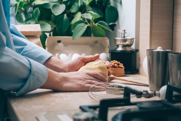 Fille pétrir la pâte dans la cuisine, gros plan. Une femme à la maison prépare de la pâte pour de délicieuses pâtisseries ou biscuits. Contexte culinaire.