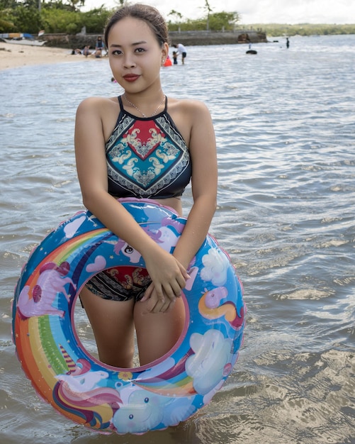 Une fille philippine sur la plage de San Remeigo avec une licorne gonflable flottante