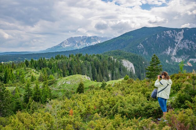 Une fille photographe fait un instantané d'un magnifique paysage de montagne.