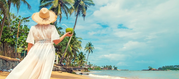 Fille sur la plage boit de la noix de coco