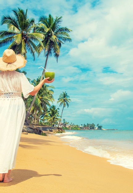 Fille sur la plage boit de la noix de coco