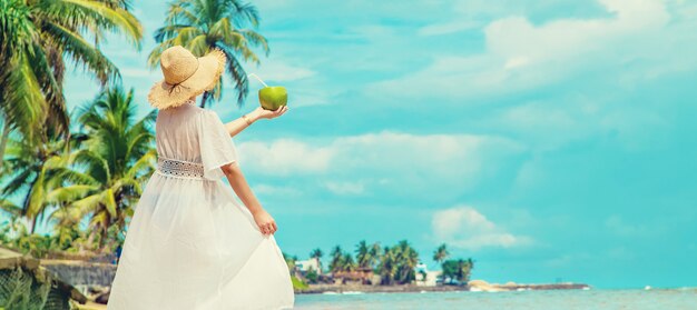 Fille sur la plage boit de la noix de coco