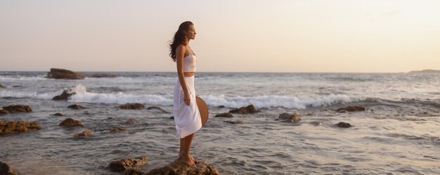 Fille de plage sensuelle devant un coucher de soleil parfait sur la mer tropicale