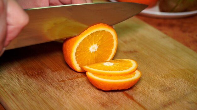 Fille sur une planche de bois coupe avec un couteau une vitamine orange juteuse mûre