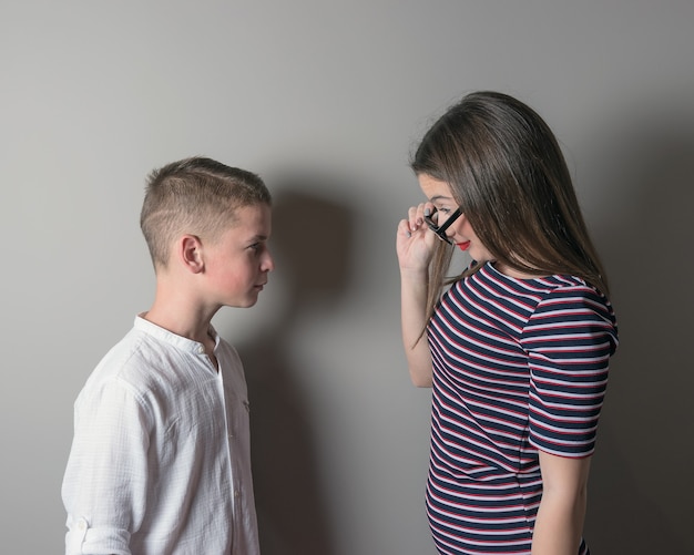 Fille plus âgée gronder un jeune garçon sur fond gris