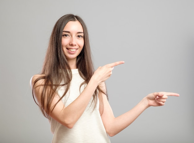 Fille pointant isolé sur gris