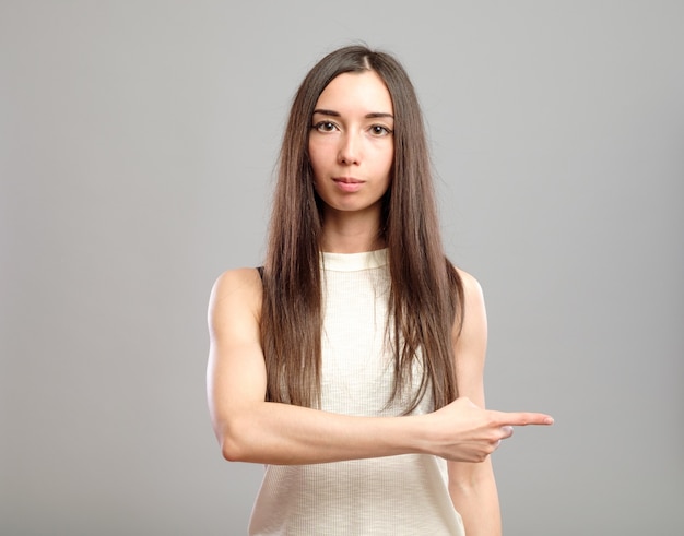 Fille pointant isolé sur gris