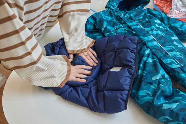 La fille pompe l'air avec un aspirateur à partir d'un sac sous vide avec des vêtements Le concept de stockage et de transport de vêtements Sac étanche peu encombrant