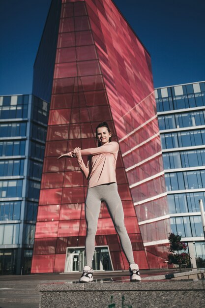 Fille de port en vêtements de sport de mode faisant des exercices de fitness yoga dans la rue, sports de plein air, style urbain