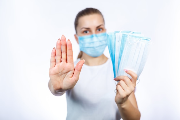 Une fille portant un masque médical de protection tient dans ses mains des moyens de protéger les voies respiratoires du virus.