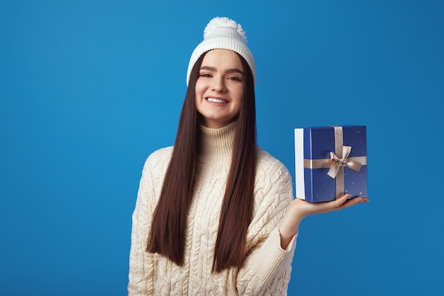 Fille portant un pull oversize blanc et un chapeau tenant une boîte présente pour