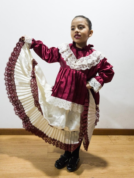 Photo fille portant des vêtements traditionnels alors qu'elle se tient contre le mur