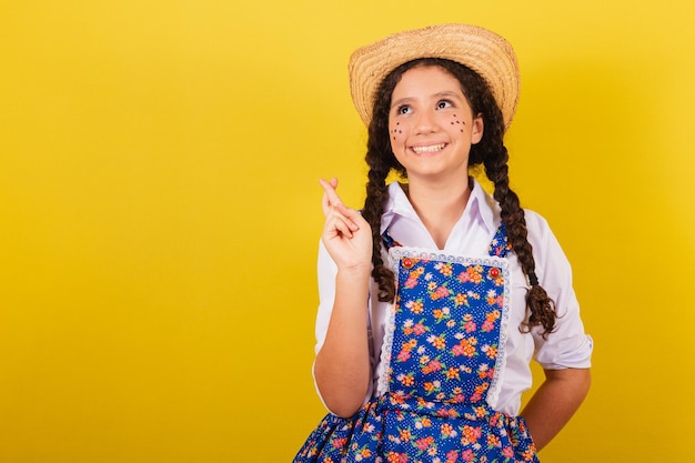 Fille portant des vêtements typiques pour Festa Junina Croisons les doigts en se tordant pour la fête d'Arraia