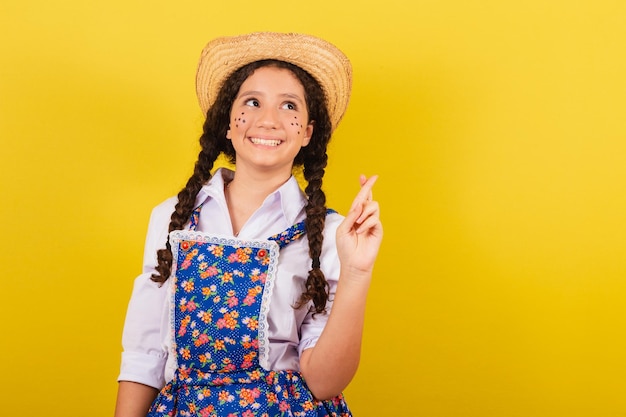 Fille portant des vêtements typiques pour Festa Junina Croisons les doigts en se tordant pour la fête d'Arraia