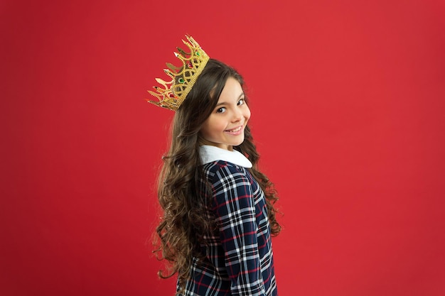 Fille porter fond rouge couronne. Concept d'enfant gâté. Princesse égocentrique. Le monde tourne autour de moi. L'enfant porte une princesse de symbole de couronne d'or. Chaque fille qui rêve devient princesse. Dame petite princesse.