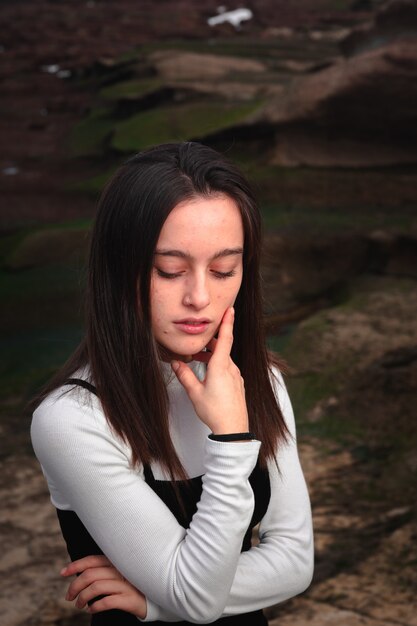 Fille posant avec une robe noire et blanche dans une crique rocheuse de la côte basque.