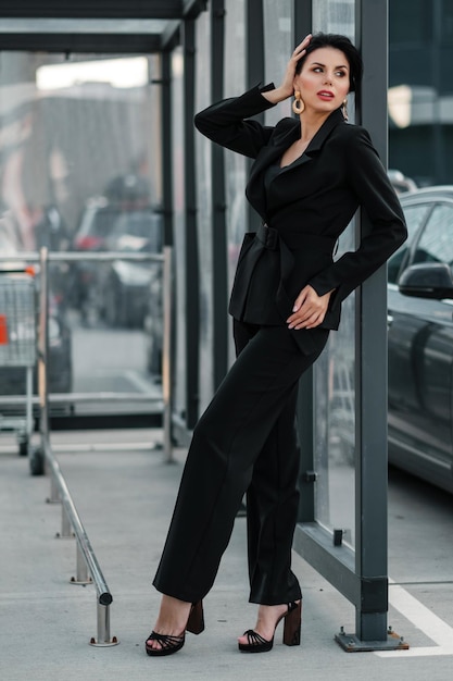 Fille posant en tailleur-pantalon noir à l'extérieur et regardant la caméra