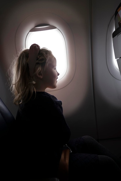 Fille positive dans l'avion près de la fenêtre