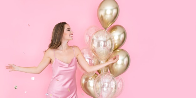 Une fille positive et heureuse célèbre le nouvel an ou une fête d'anniversaire avec des ballons à air lançant des confettis