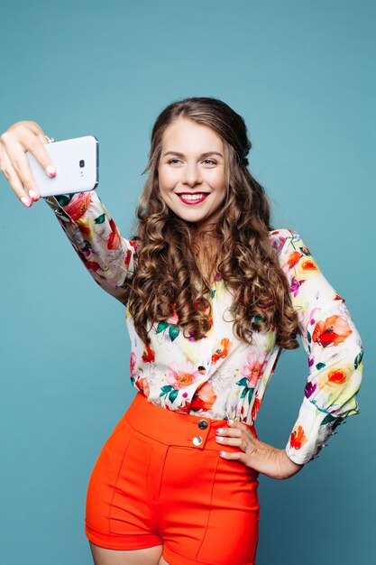 Fille de positivité souriant et clouant autoportrait au téléphone intelligent.