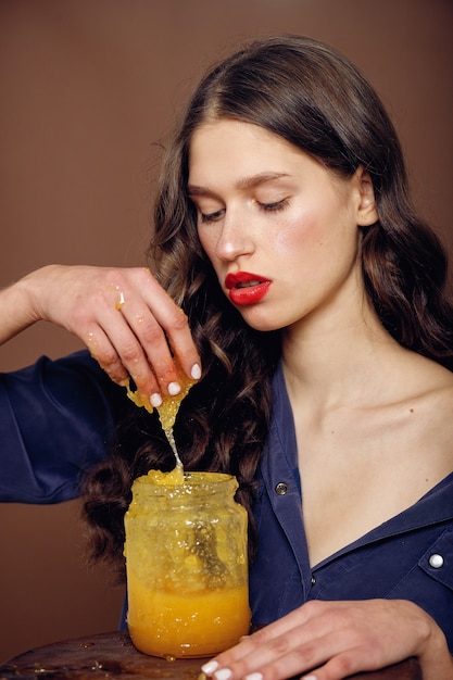 Fille avec pot de miel. Concept d'alimentation saine, régime alimentaire, dessert. belle fille sourit et touche le miel avec les mains d'un pot