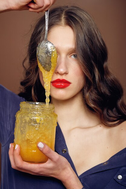 Fille avec pot de miel. Concept d'alimentation saine, régime alimentaire, dessert. belle fille tient une cuillère en argent avec du miel