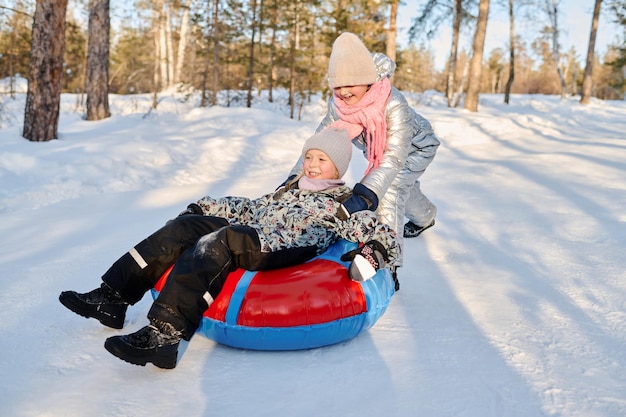 Une fille poussant un tube de neige avec un ami.