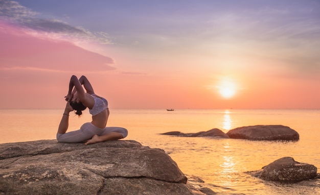 Photo fille pratiquant le yoga sur un rocher