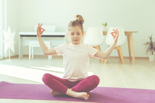 Photo une fille pratiquant le yoga sur un tapis à la maison.