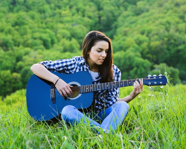 Fille sur un pré vert jouant de la guitare