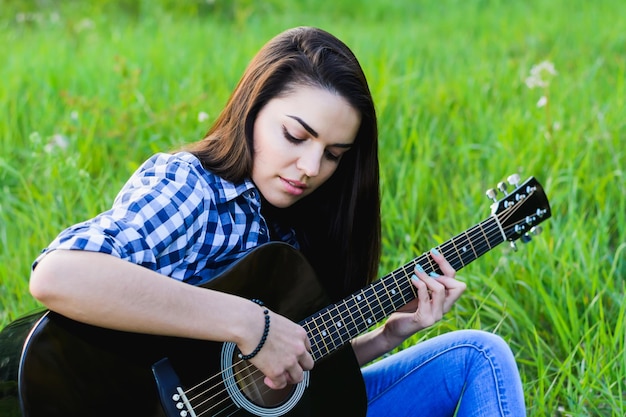 Fille sur un pré vert jouant de la guitare