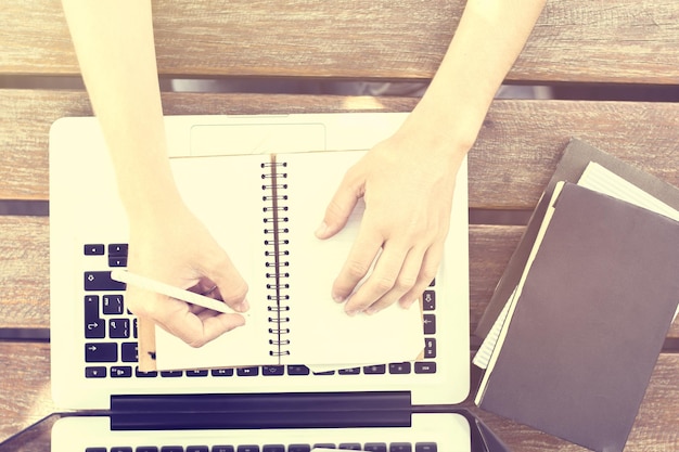 Fille prenant des notes dans le journal et des livres sur la table en bois