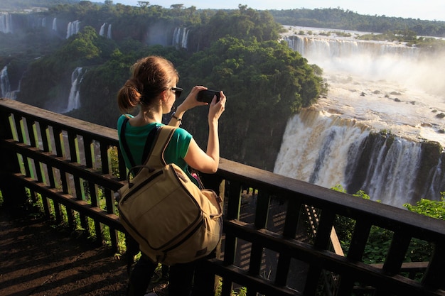 Fille prenant une photo de la cascade d'Iguassu avec un smartphone