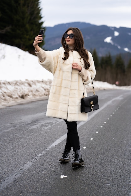 Fille prenant une photo d'elle-même sur smartphone sur les montagnes d'hiver