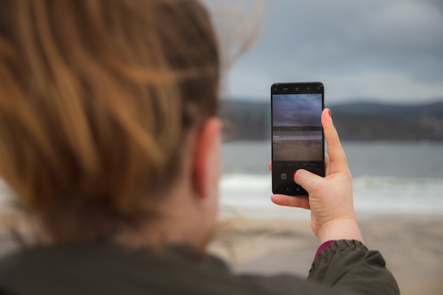 Fille prenant une photo avec son mobile de la mer