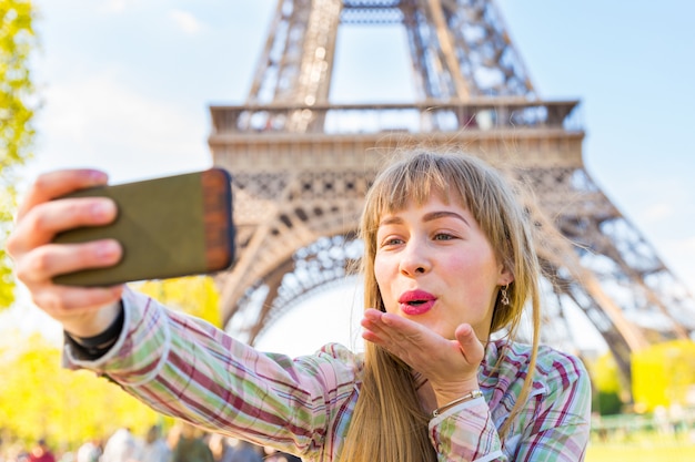 Fille prenant un selfie et souffle un baiser à Paris avec la Tour Eiffel