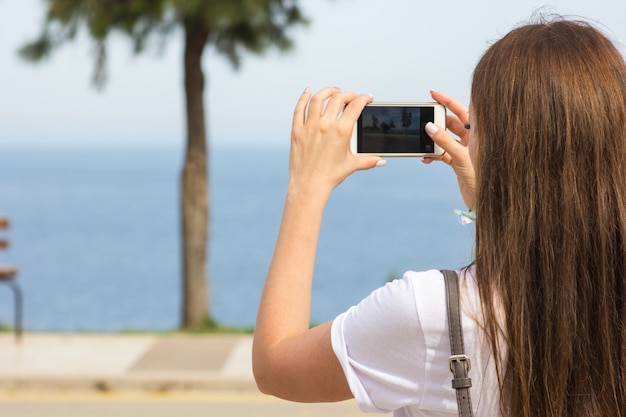 La fille prend des photos sur la beauté de la mer