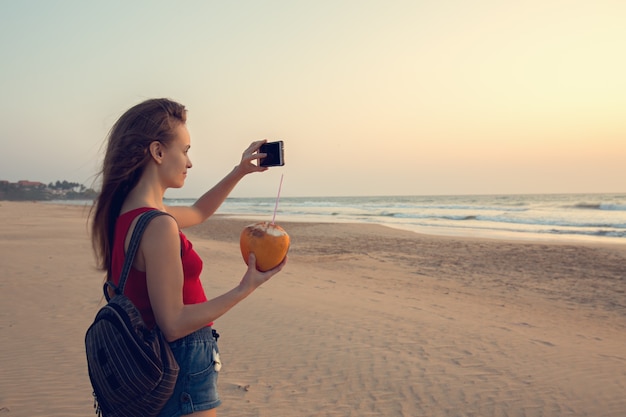 La fille prend des photos du coucher de soleil