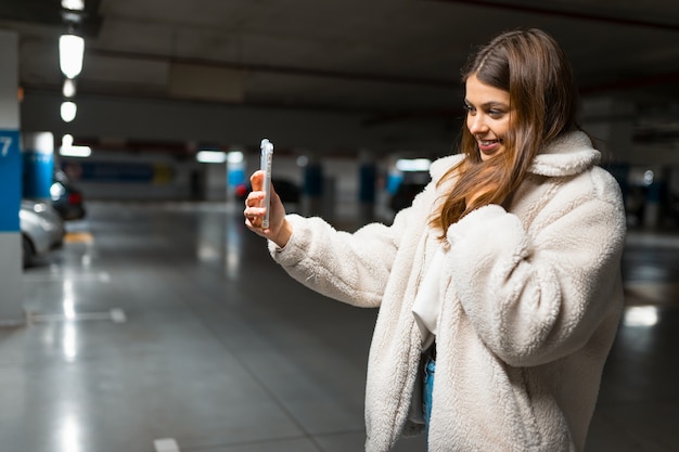 Fille prend selfie dans le parking souterrain.