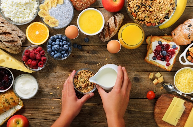 Fille Préparant Le Petit-déjeuner - Céréales Avec Yaourt, Fruits, Baies, Lait, Yaourt, Jus, Fromage. Alimentation Saine, Régime Amaigrissant, Désintoxication, Concept D'aliments Végétariens