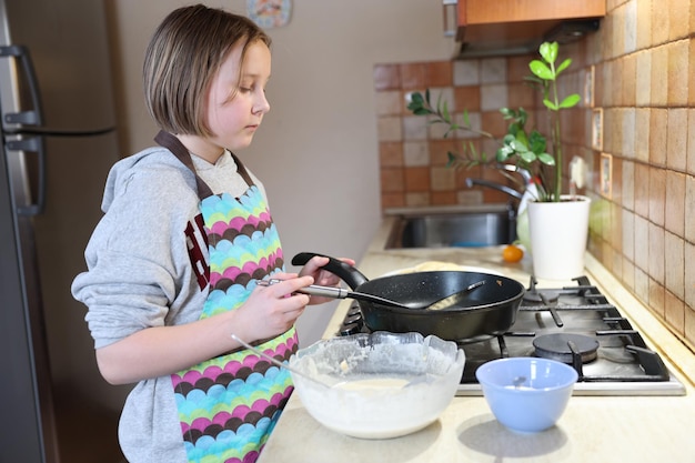 Une fille prépare des crêpes dans la cuisine