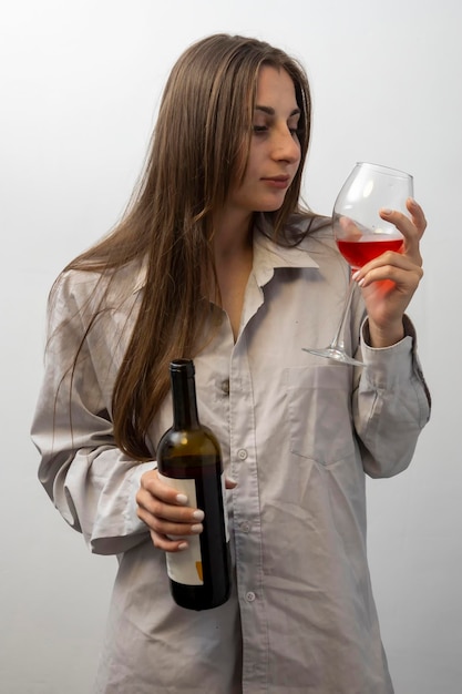 La fille près du mur avec une bouteille de vin et des verres