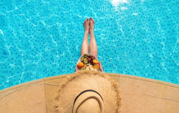 Fille près de la piscine avec des fruits. Gens.