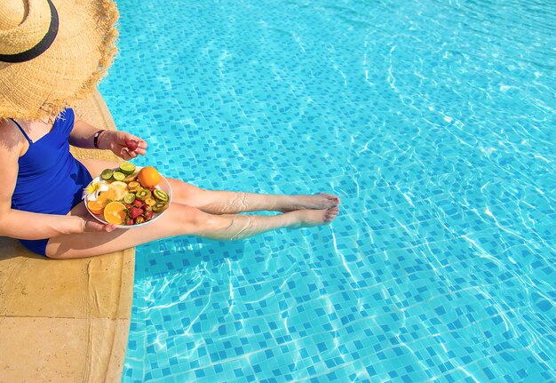 Fille près de la piscine avec des fruits