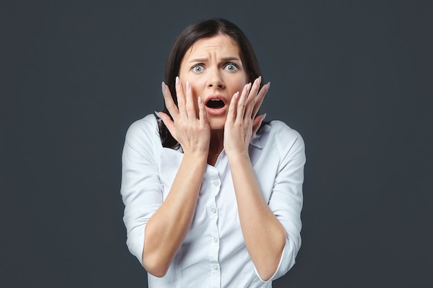 La fille presse ses mains sur son visage, ce qui montre la peur