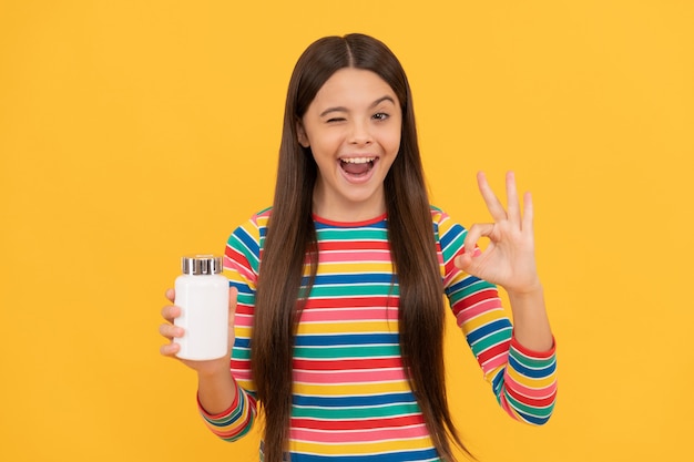 Fille avec des produits de pilules naturels. présentation du produit vitaminé. enfant heureux avec pot de pilules. tablette pour enfants. fille détiennent des multivitamines. mode de vie sain. santé de l'enfance. d'accord. complément alimentaire.