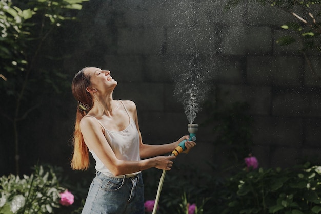 Fille profitant de l'eau dans la chaleur de l'été dans le jardin