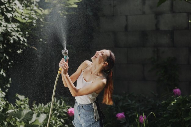 Fille profitant de l'eau dans la chaleur de l'été dans le jardin