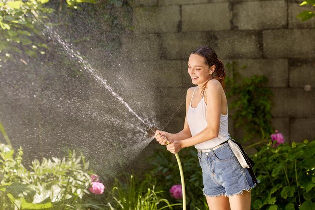 Fille profitant de l'eau dans la chaleur de l'été dans le jardin